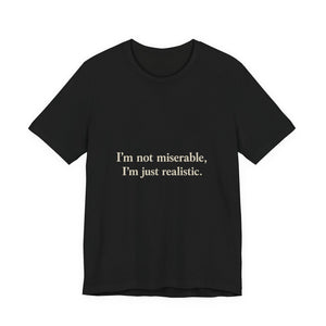 The "I'm Not Miserable. I'm Just Realistic." T-Shirt by Printify’s Old Man Snark features a black crew neck, soft Airlume cotton, and beige chest print: “I'm not miserable, I'm just realistic.”.