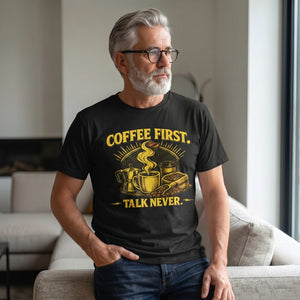 Old Man Snark black cotton t-shirt with bold yellow Coffee First Talk Never graphic worn by a man in a living room.