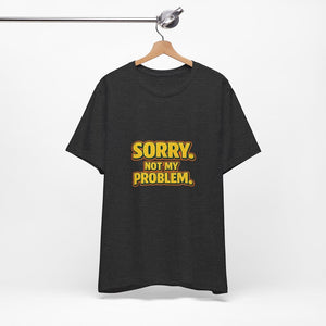 Old Man Snark black cotton t-shirt with retro gold and orange Sorry. Not My Problem. text on a wooden hanger.