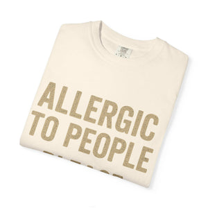 Folded white T-shirt with "Allergic to People, Please Maintain Distance" printed in bold beige letters