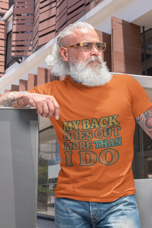 Man wearing whimsical unisex heavy cotton tee with funny green and black text "My back goes out more than I do" outdoors.