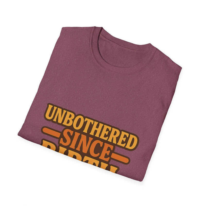 Folded maroon unisex cotton t-shirt with orange "Unbothered Since Birth" text design