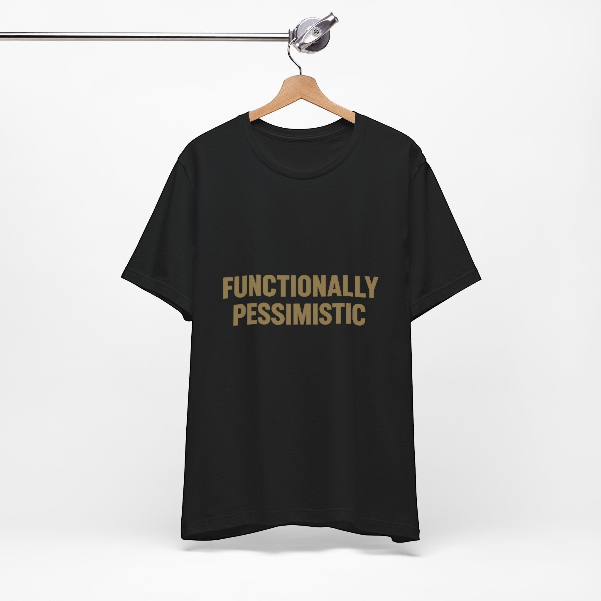 The "Functionally Pessimistic" T-Shirt by Old Man Snark (Printify) hangs on a wooden hanger, featuring bold beige lettering on black Airlume cotton, set against a plain white background.