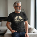 An older man with gray hair and a beard, wearing glasses and a Printify "I Have No Time For Stupidity" T-Shirt by Old Man Snark, sits on a couch in a modern living room.