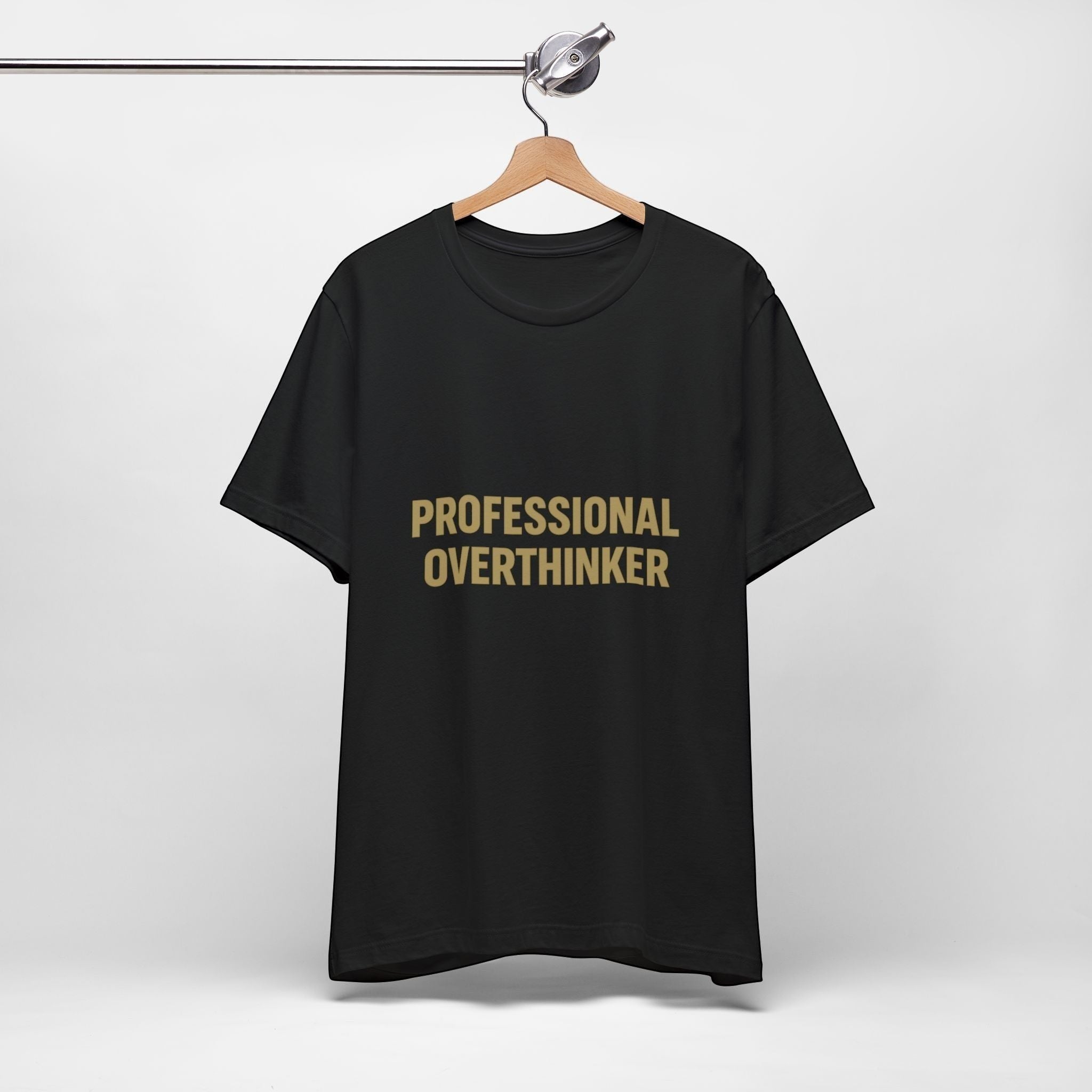 The "Professional Overthinker" T-Shirt by Printify, made with 100% Airlume cotton, features bold gold lettering on black and hangs on a wooden hanger against a plain white background.