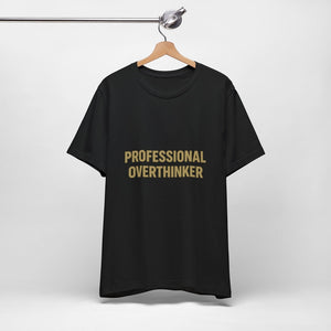The "Professional Overthinker" T-Shirt by Printify, made with 100% Airlume cotton, features bold gold lettering on black and hangs on a wooden hanger against a plain white background.