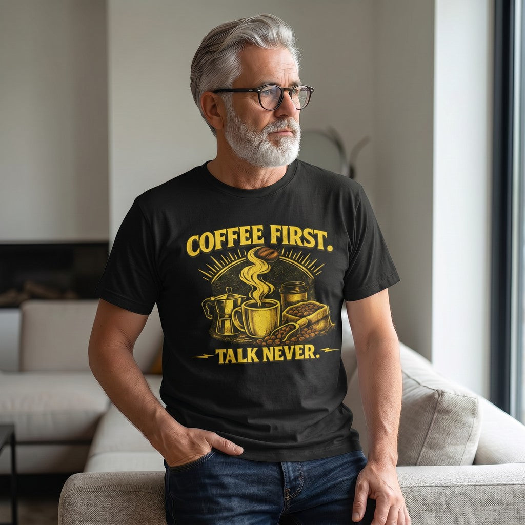 Old Man Snark black cotton t-shirt with bold yellow Coffee First Talk Never graphic worn by a man in a living room.