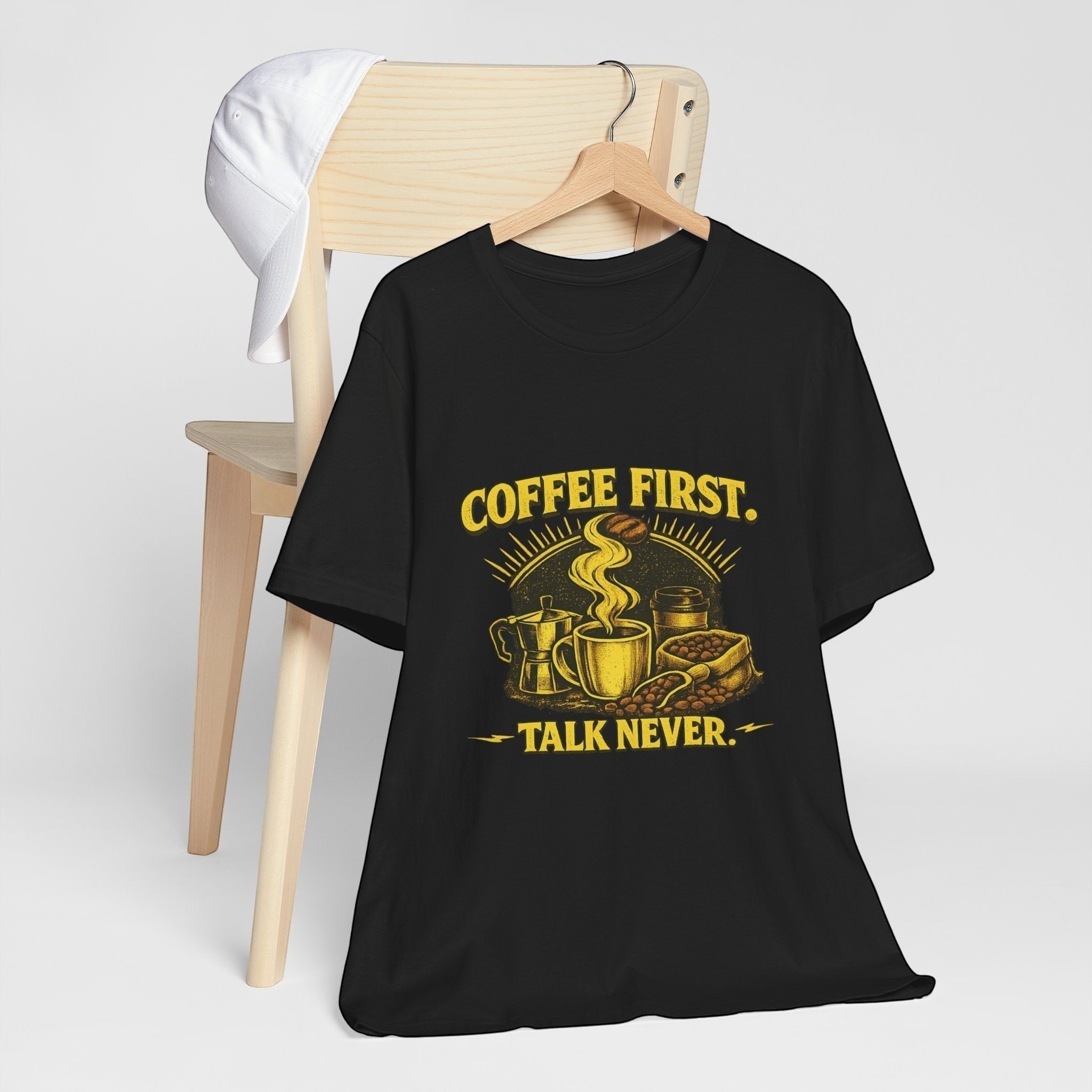 Old Man Snark black cotton t-shirt with yellow graphic saying "COFFEE FIRST. TALK NEVER." featuring coffee cup, moka pot, and beans.