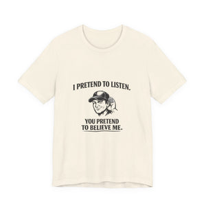 Old Man Snark off-white 100% cotton t-shirt with a graphic that reads "I PRETEND TO LISTEN." above a man cupping his ear, and "YOU PRETEND TO BELIEVE ME." below.